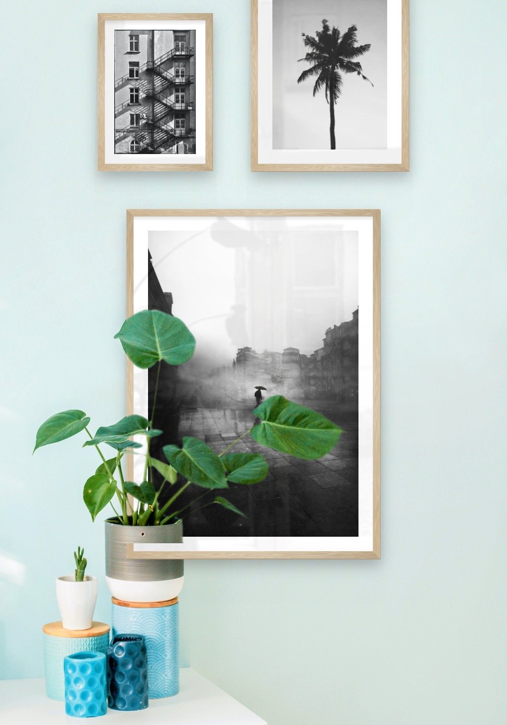 Gallery wall with picture frames in wood in sizes 21x30, 30x40 and 50x70 with prints "Stairs on the facade", "Palm" and "Rainy city"