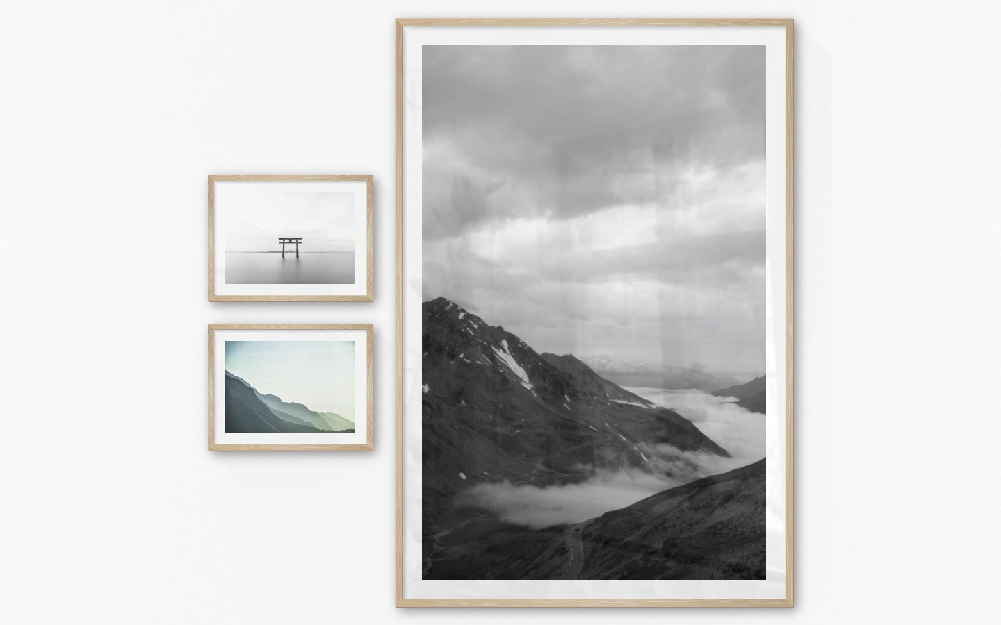 Gallery wall with picture frames in wood in sizes 30x40 and 100x150 with prints "Pillars in the water", "Foggy mountain" and "Road among mountains"