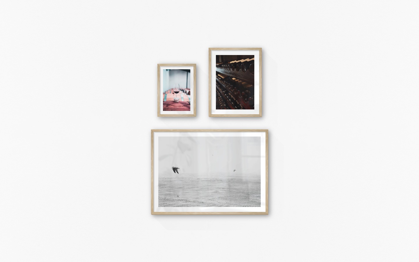 Gallery wall with picture frames in wood in sizes 21x30, 30x40 and 50x70 with prints "Wine glasses in barrels", "Wine storage" and "Birds over the sea"