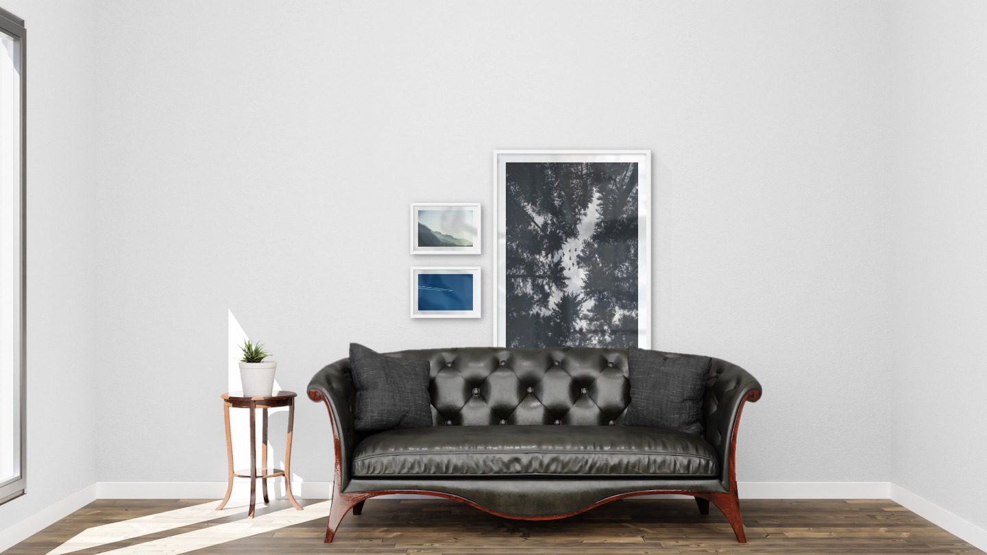 Gallery wall with picture frames in white in sizes 21x30 and 70x100 with prints "Foggy mountain", "Airplanes in the air" and "Wooden tops and birds"