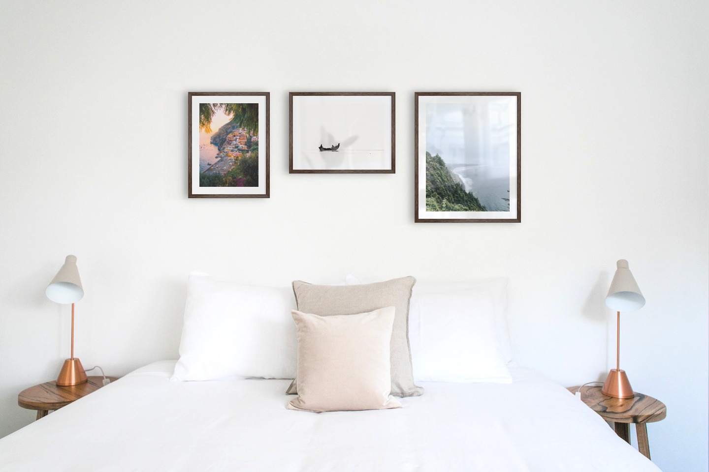 Gallery wall with picture frames in dark wood in sizes 30x40 and 40x50 with prints "City by the sea", "People in boat" and "Rocks facing the water"