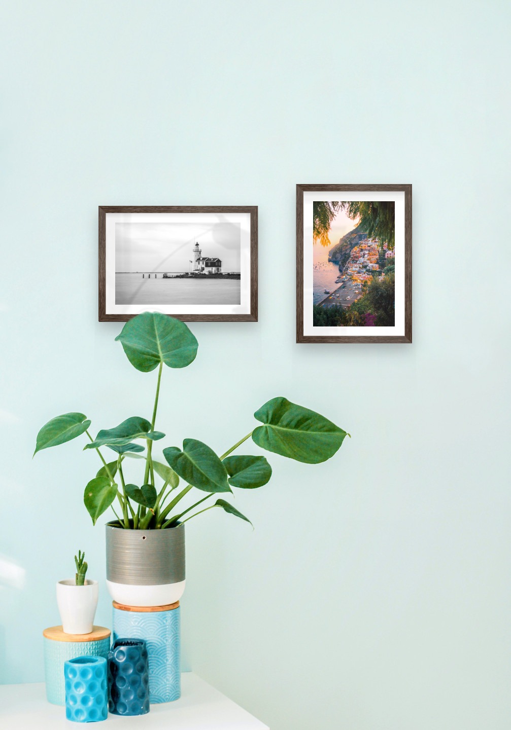 Gallery wall with picture frames in dark wood in sizes 21x30 with prints "Pier with building" and "City by the sea"