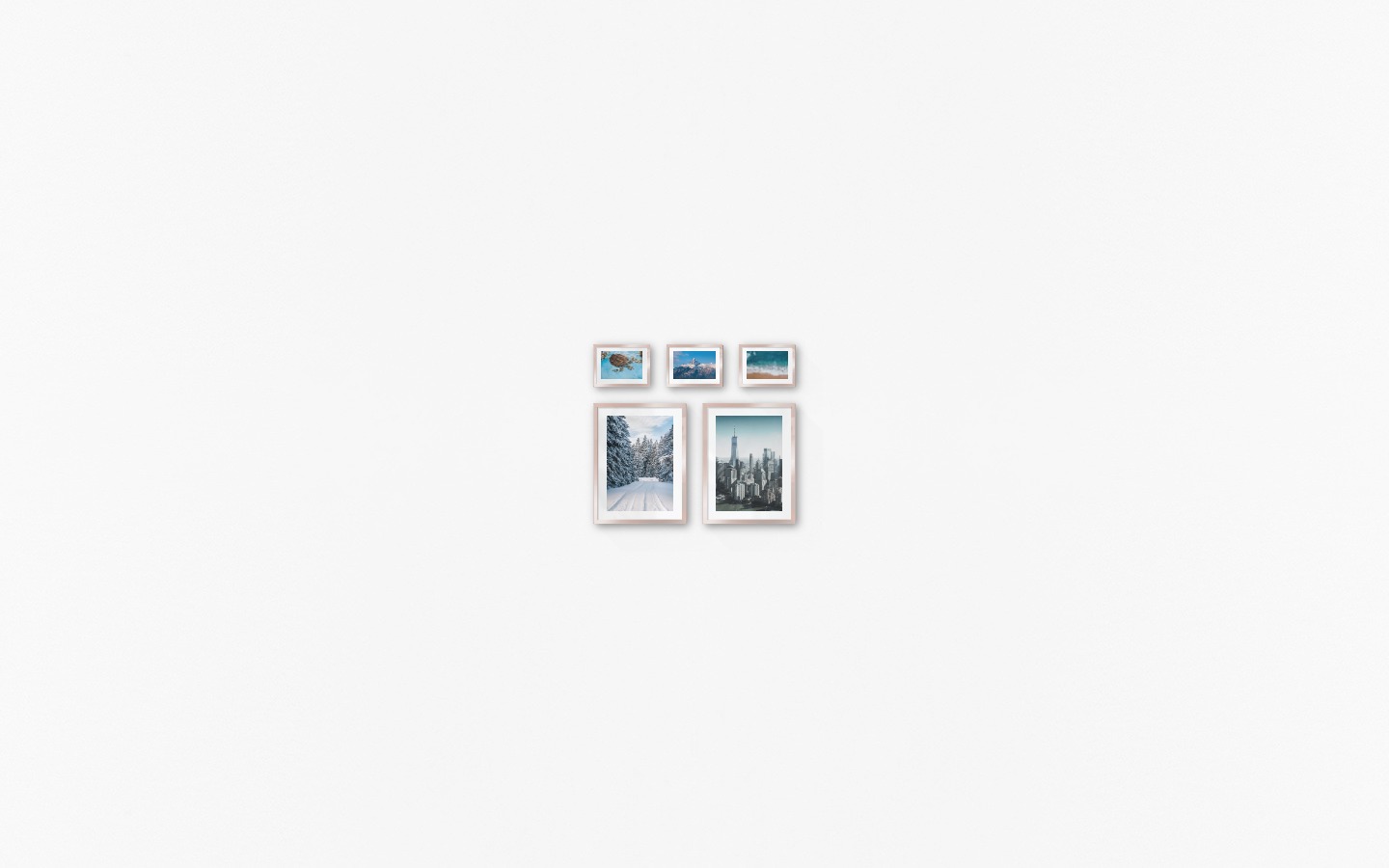 Gallery wall with picture frames in copper in sizes 30x40 and 13x18 with prints "Snowy road", "Gray and blue skyline", "Turtle in the water", "Top above the clouds" and "Waves on the beach"
