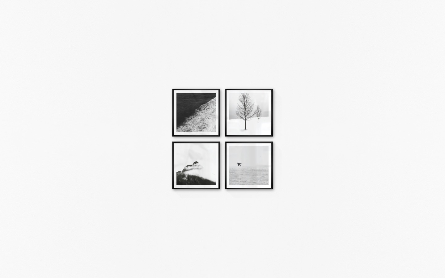 Gallery wall with picture frames in black in sizes 50x50 with prints "Swell from waves", "Trees in the snow", "Mountain peaks in fog" and "Birds over the sea"