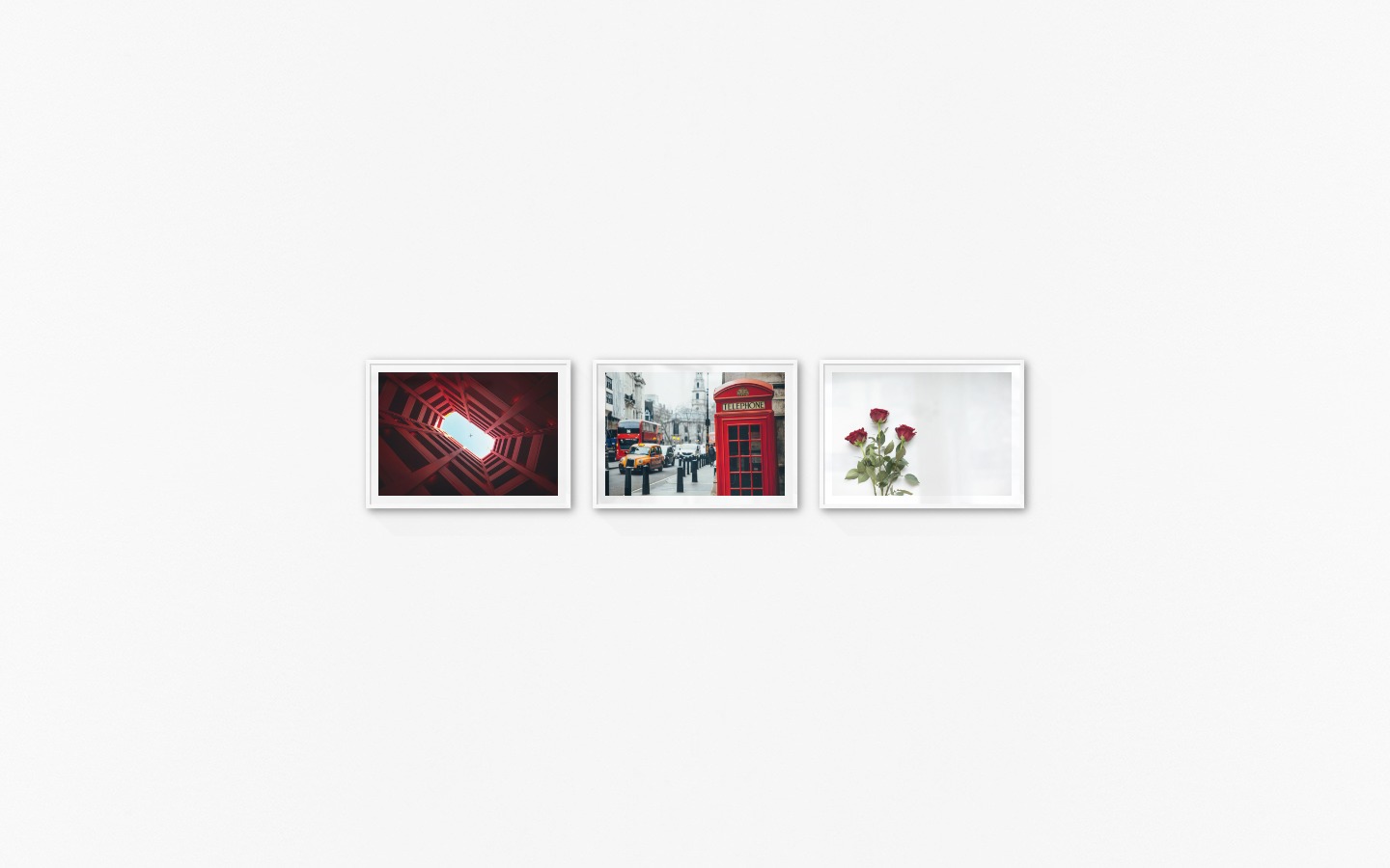 Gallery wall with picture frames in white in sizes 50x70 with prints "Airplane above building", "Telephone kiosk" and "Red roses"