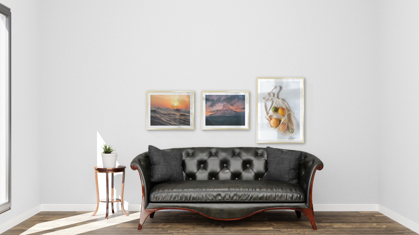 Gallery wall with picture frames in gold in sizes 40x50 and 50x70 with prints "Waves and the sun", "Sunset and mountains" and "Fruit in a bag"