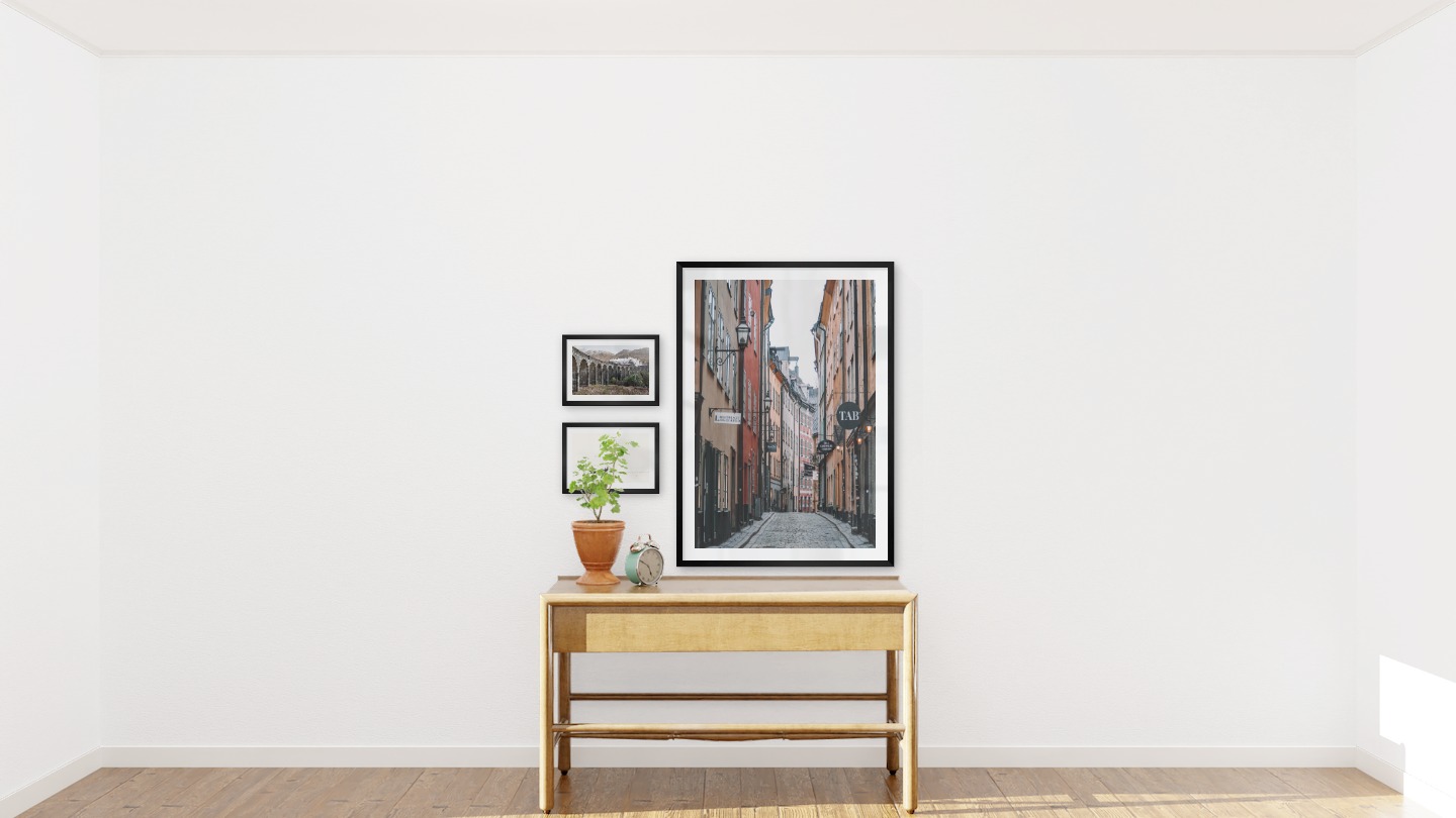 Gallery wall with picture frames in black in sizes 21x30 and 70x100 with prints "Train on bridge", "People in boat" and "Old town in Stockholm"